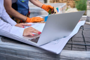 immagine di un computer sopra un foglio con disegnato un progetto